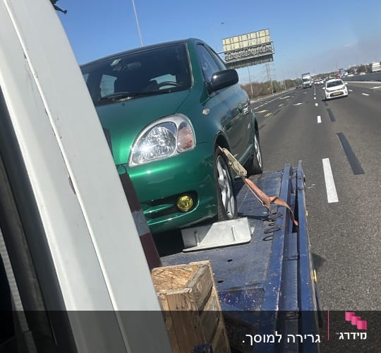 רכב ירוק על גרר בכביש מהיר
